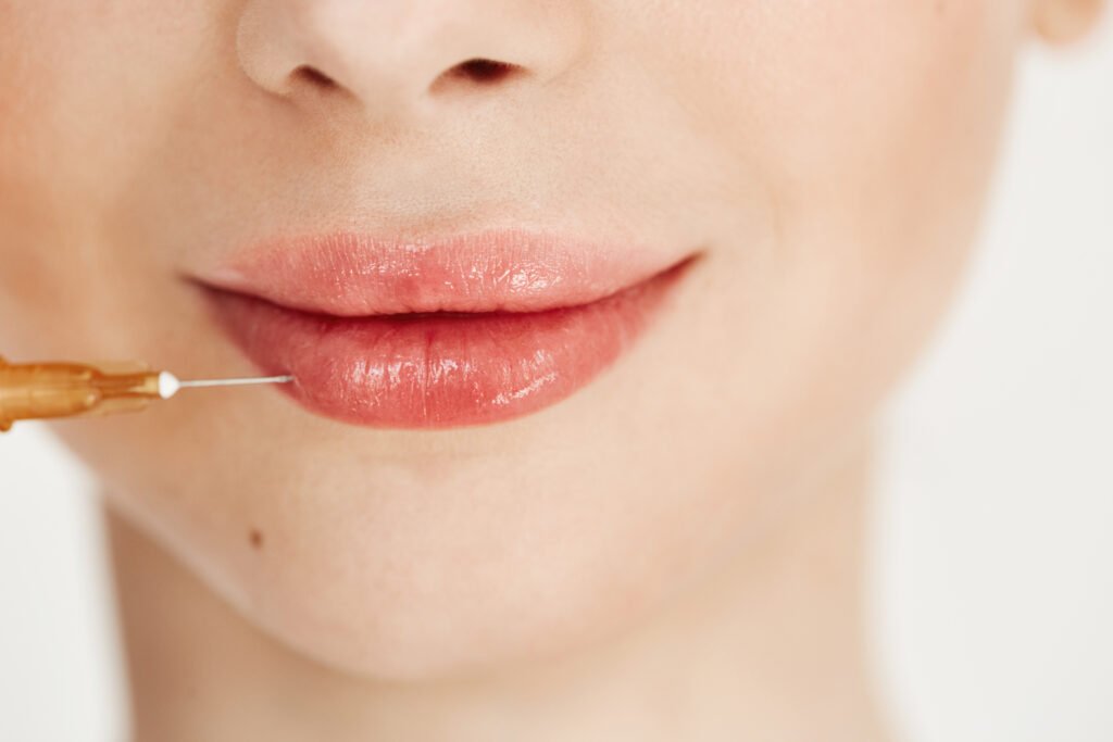 Close up photo of injection in lips over white background. Lips treatment.